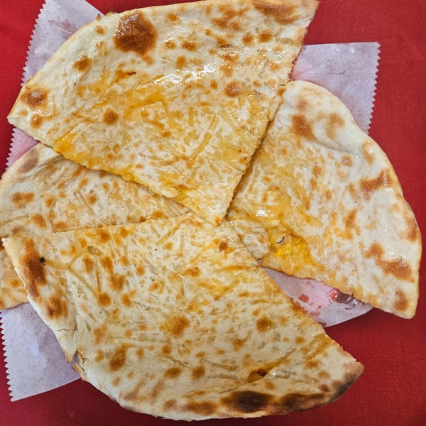 Four pieces of golden-brown cheese naan bread, glistening with butter, on a red surface.